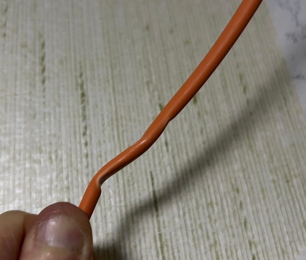 Oranges Netzwerkkabel, an einer Stelle sichtbar flach gedrückt