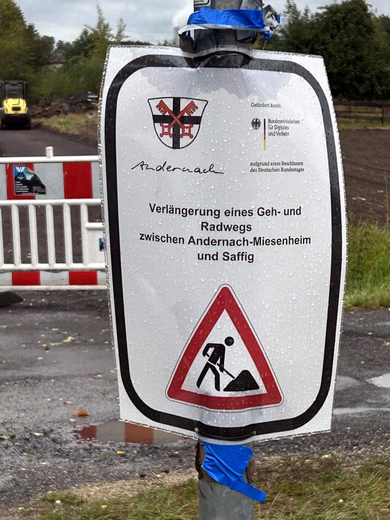Laminierter A4-Zettel an Mast
[Logo Stadt Andernach]
[Logo Gefördert durch Bundesministerium für Digitales und Verkehr aufgrund eines Beschlusses des Deutschen Bundestages]

Verlängerung eines Geh- und Radwegs zwischen Andernach-Miesenheim und Saffig

[Schild Baustelle]