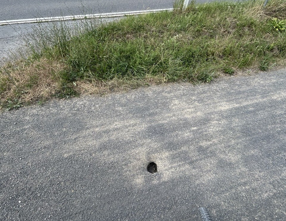 Loch im der Mitte des Weges mit neuem Belag. Drunter scheinen Teile unterspült.